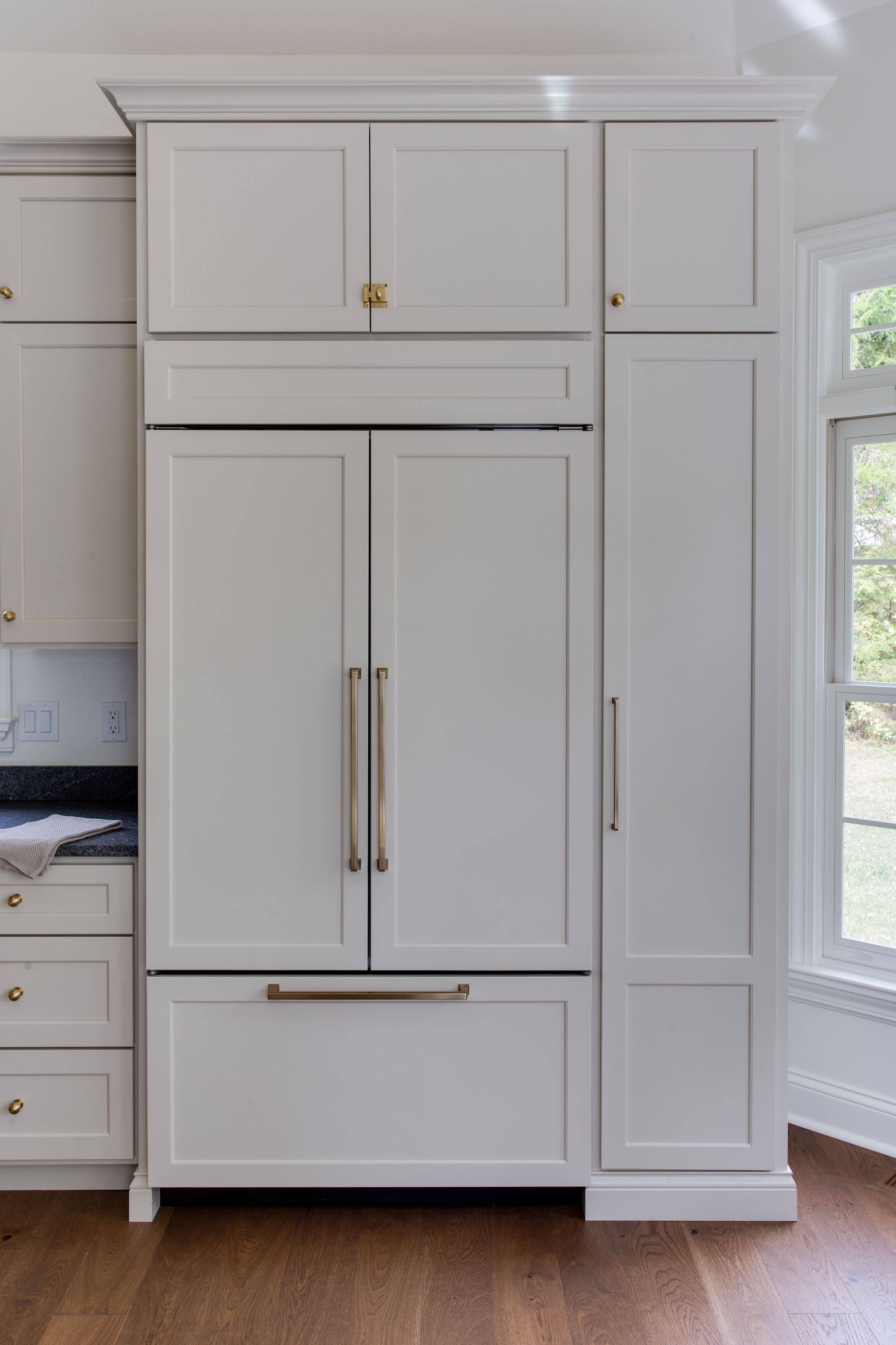 A kitchen with white cabinets and a window
