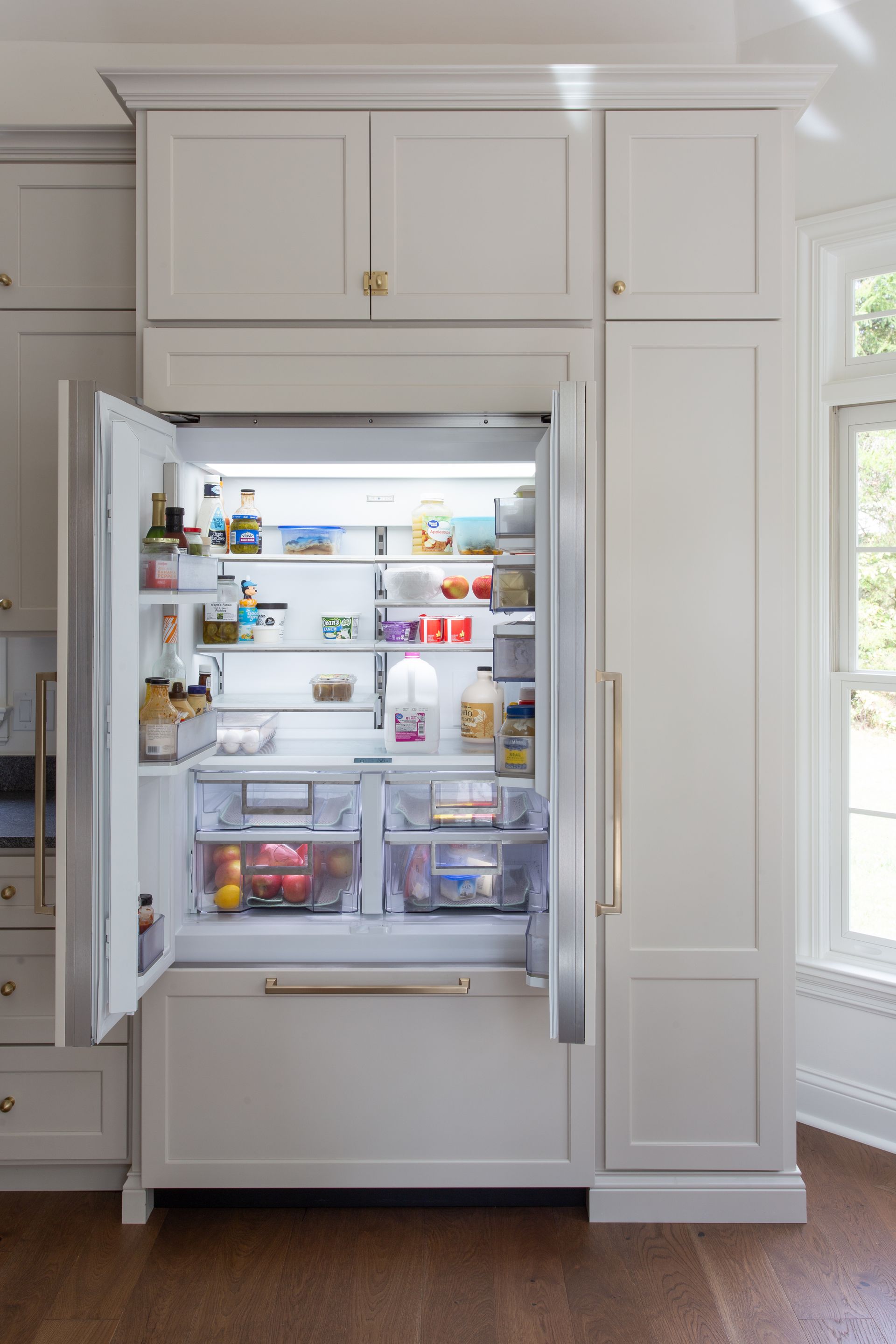 The refrigerator is open and filled with lots of food.
