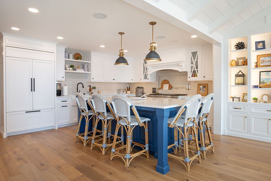 A beautiful custom kitchen with a blue island and white cabinets and stools.