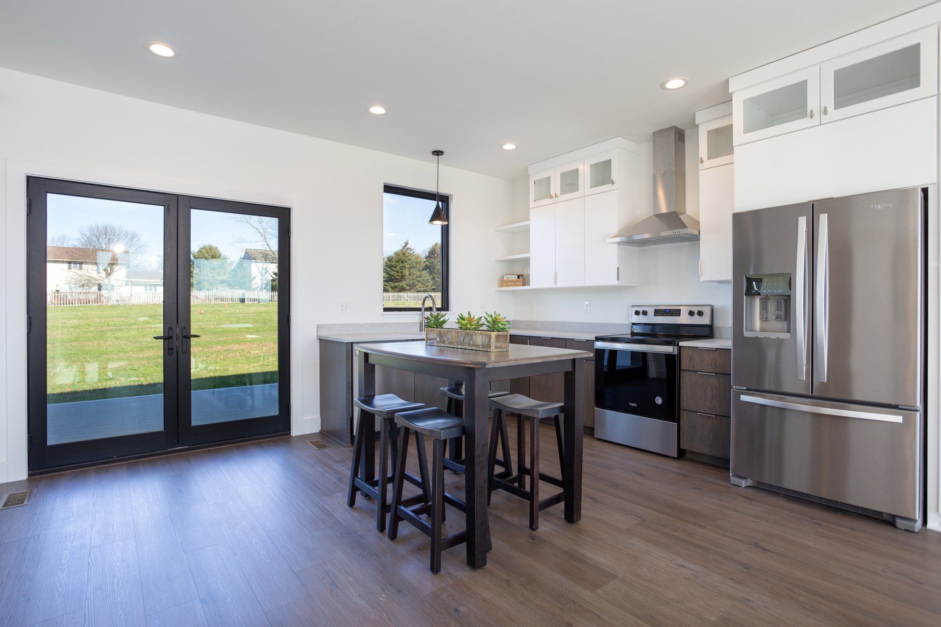 A kitchen with stainless steel appliances and a table with stools.