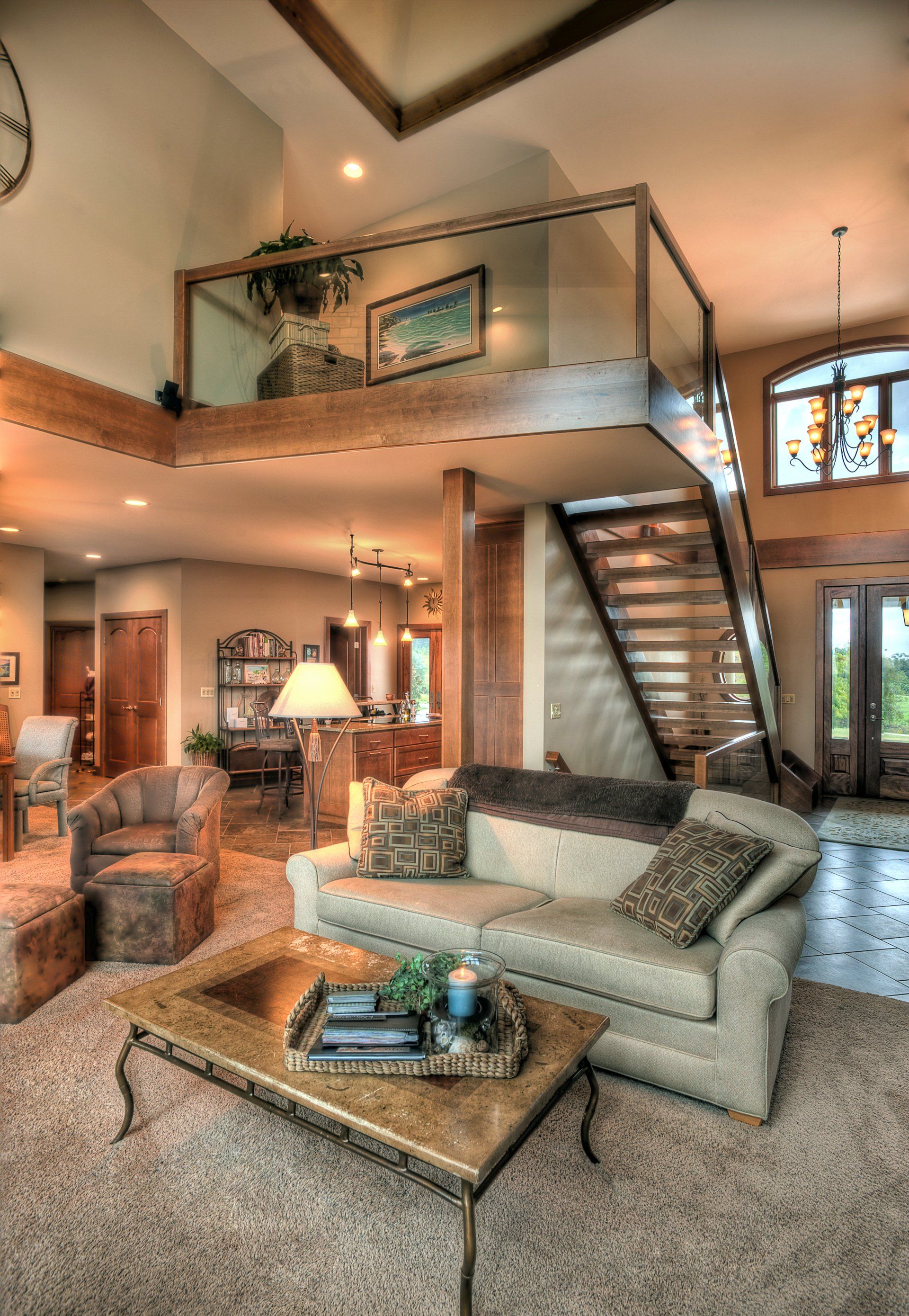 A living room with a couch , coffee table , chairs and stairs.