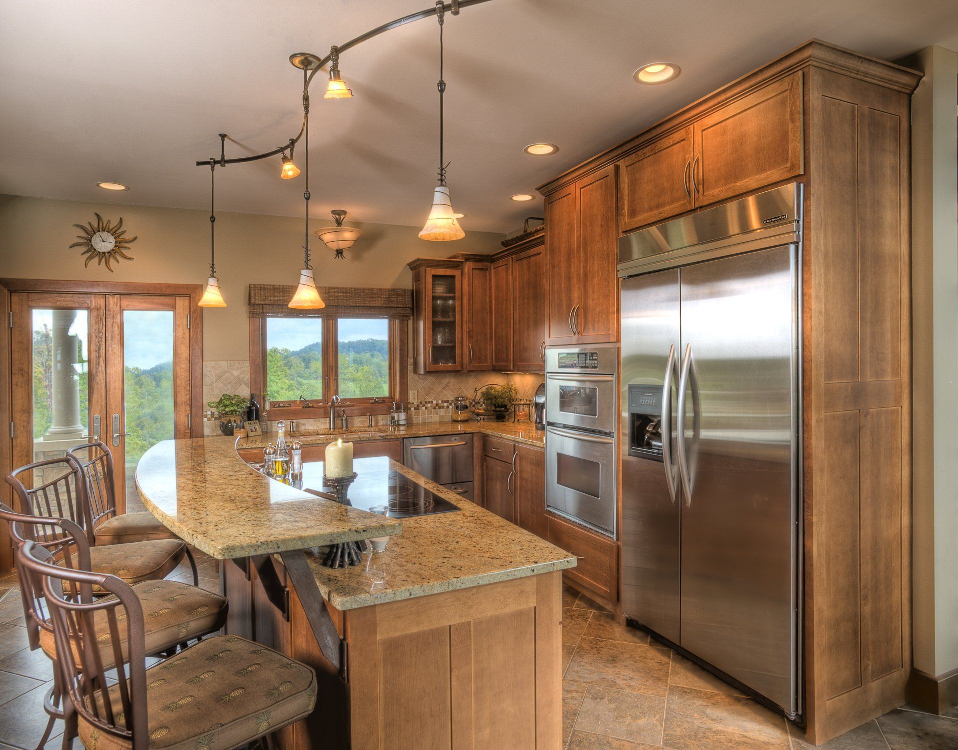 A kitchen with stainless steel appliances, wooden cabinets, and big island with stools. .