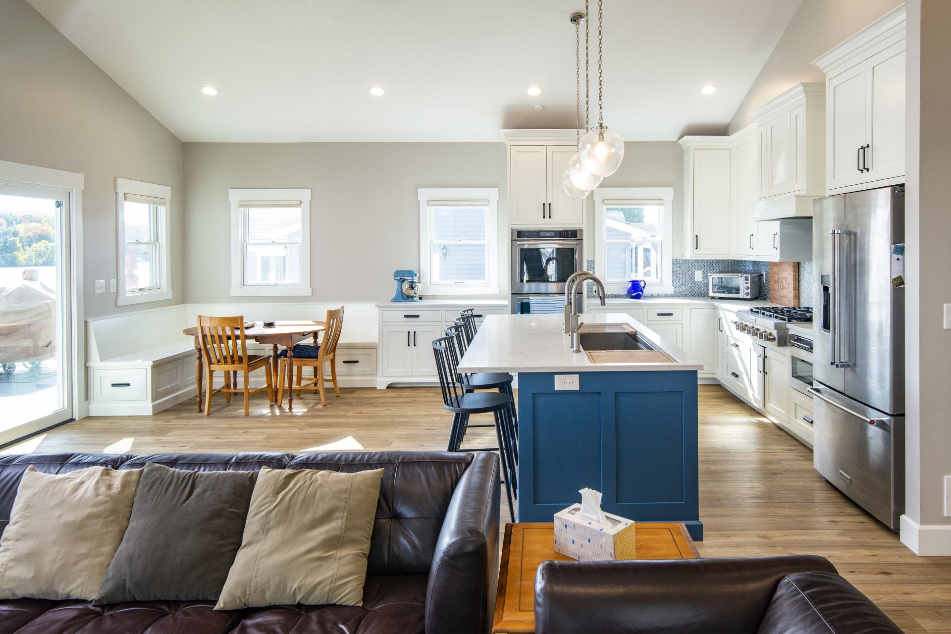 A living room filled with furniture and a kitchen with stainless steel appliances.