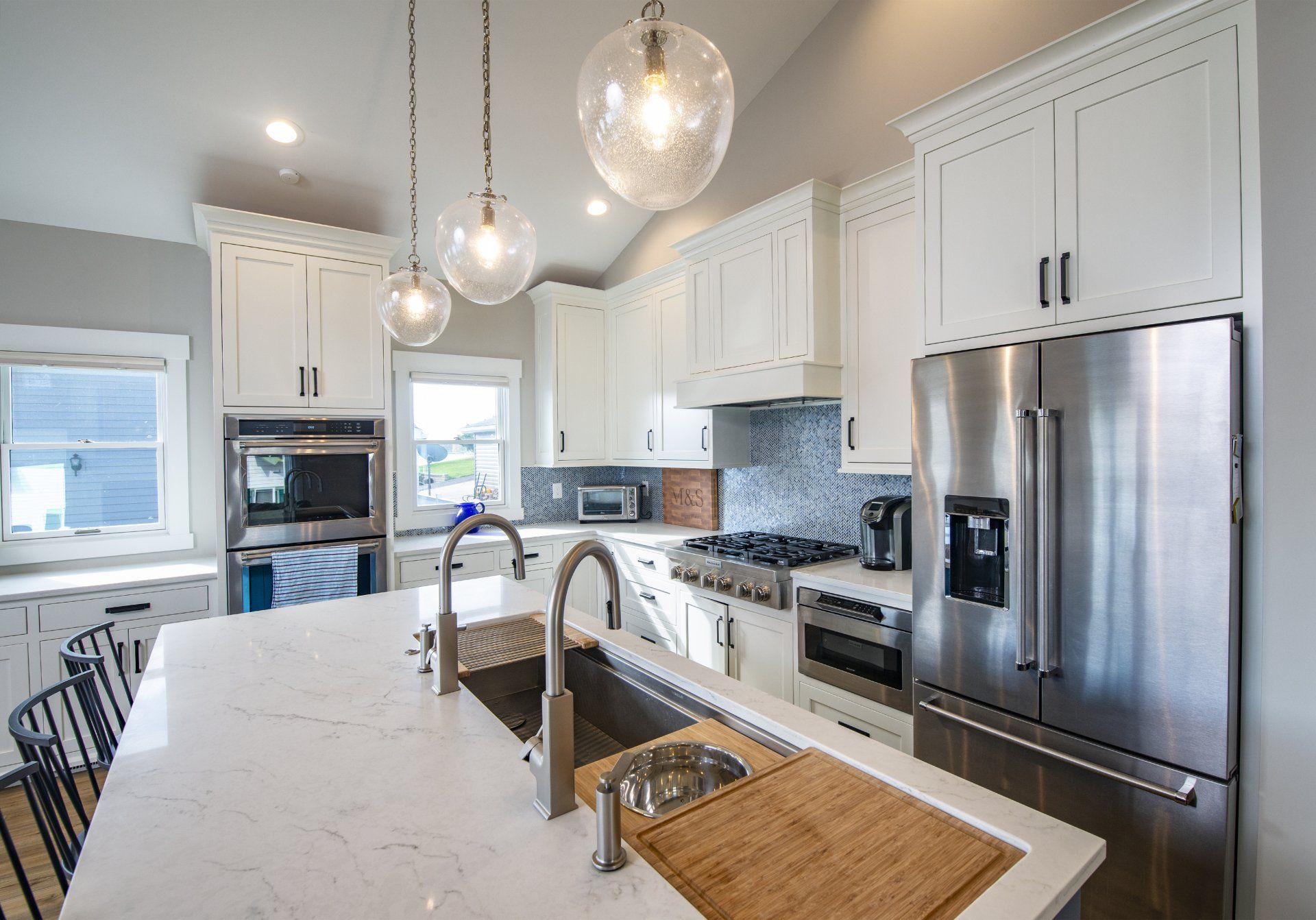 A kitchen with an island,  stainless steel appliances, and white cabinets.