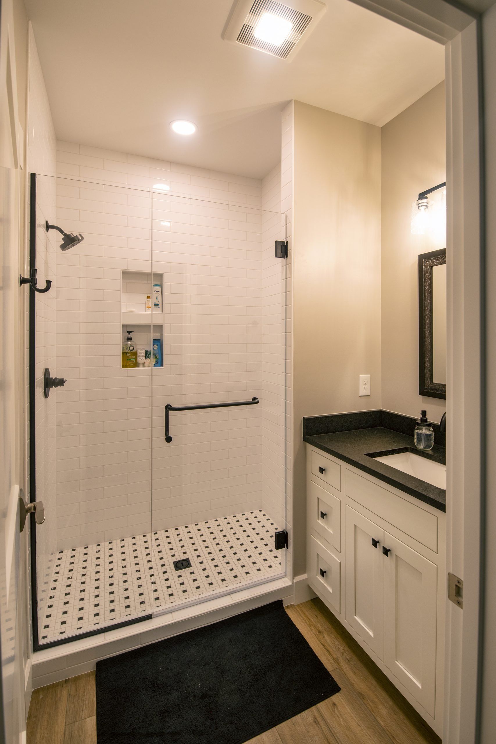 A bathroom with a walk in shower , sink and mirror.