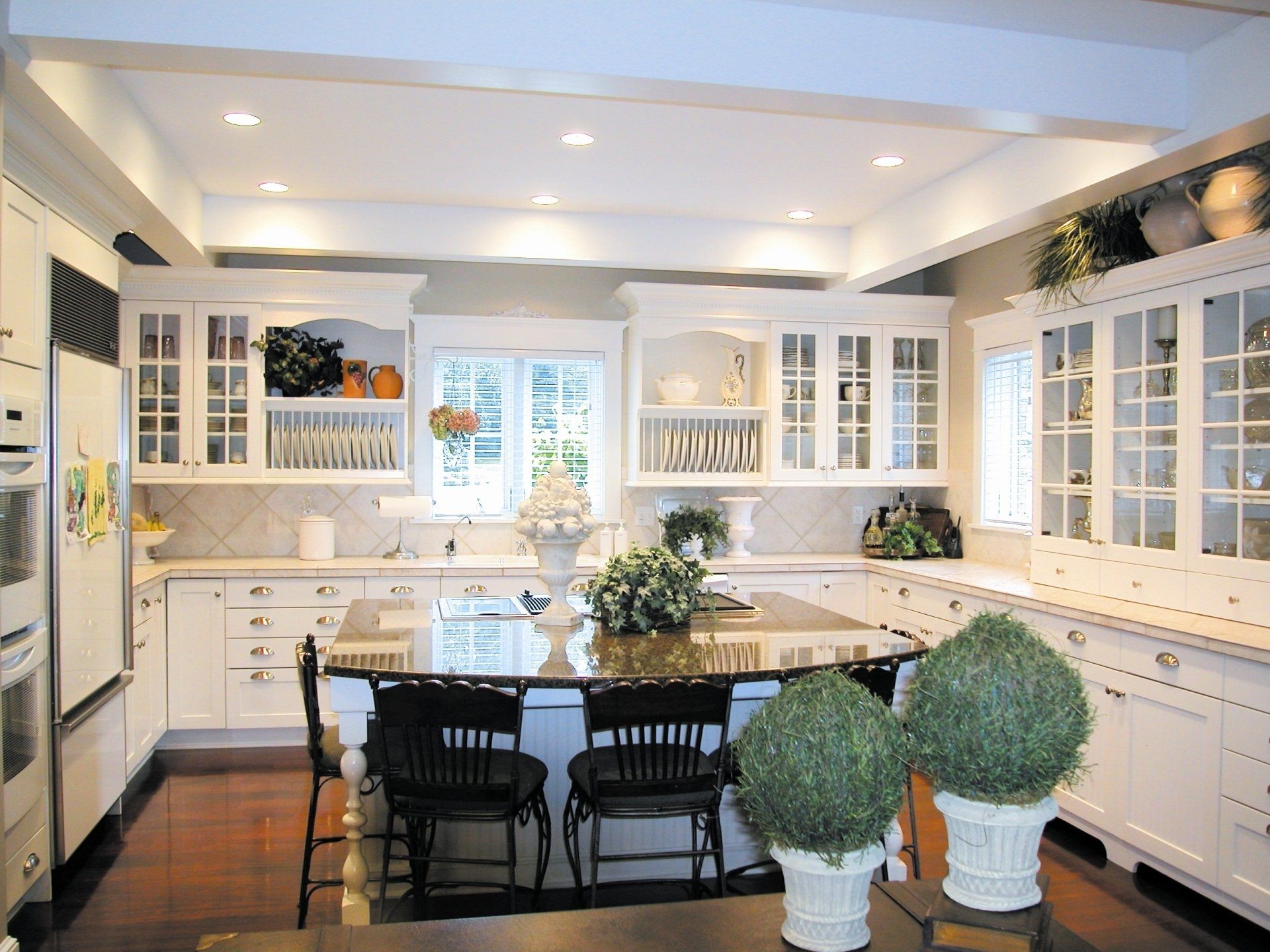 A kitchen with white cabinets and a large island/table. 