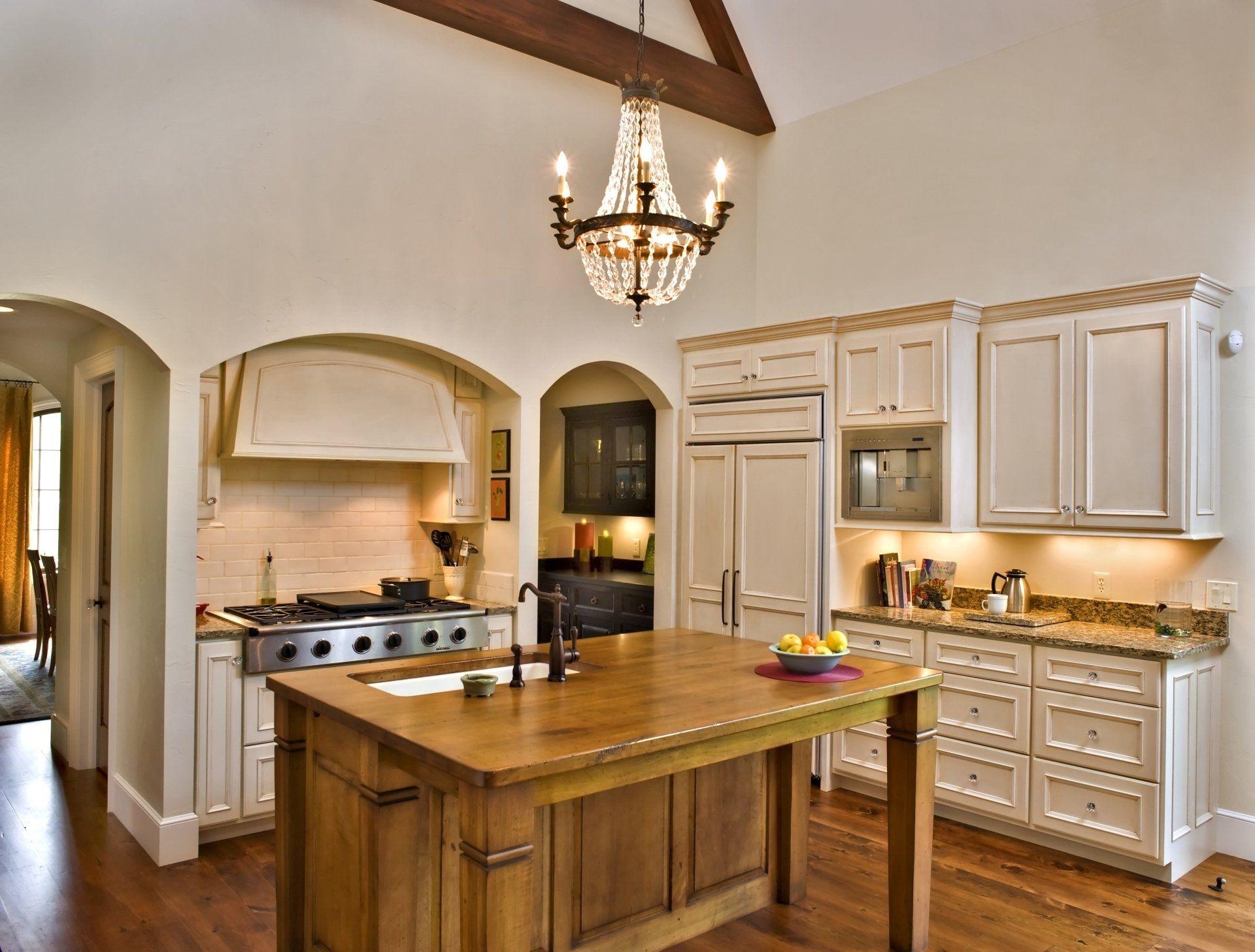 A kitchen with white cabinets and a large wooden island.