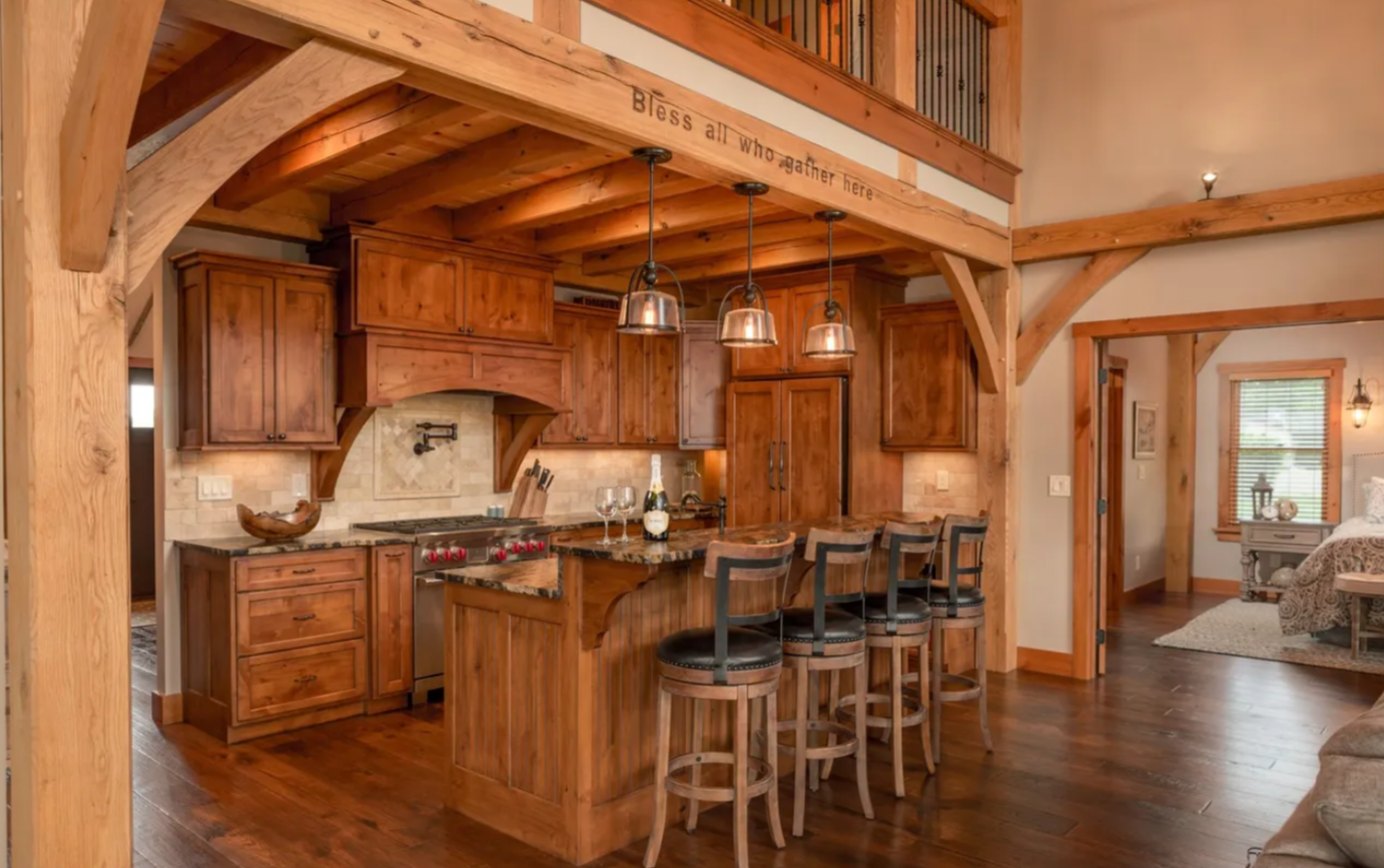 A kitchen in a log cabin, custom wooden cabinets, and stools.