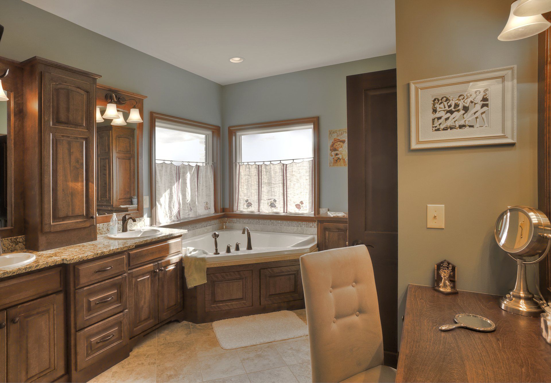 A bathroom with a tub , sink , mirror and chair.