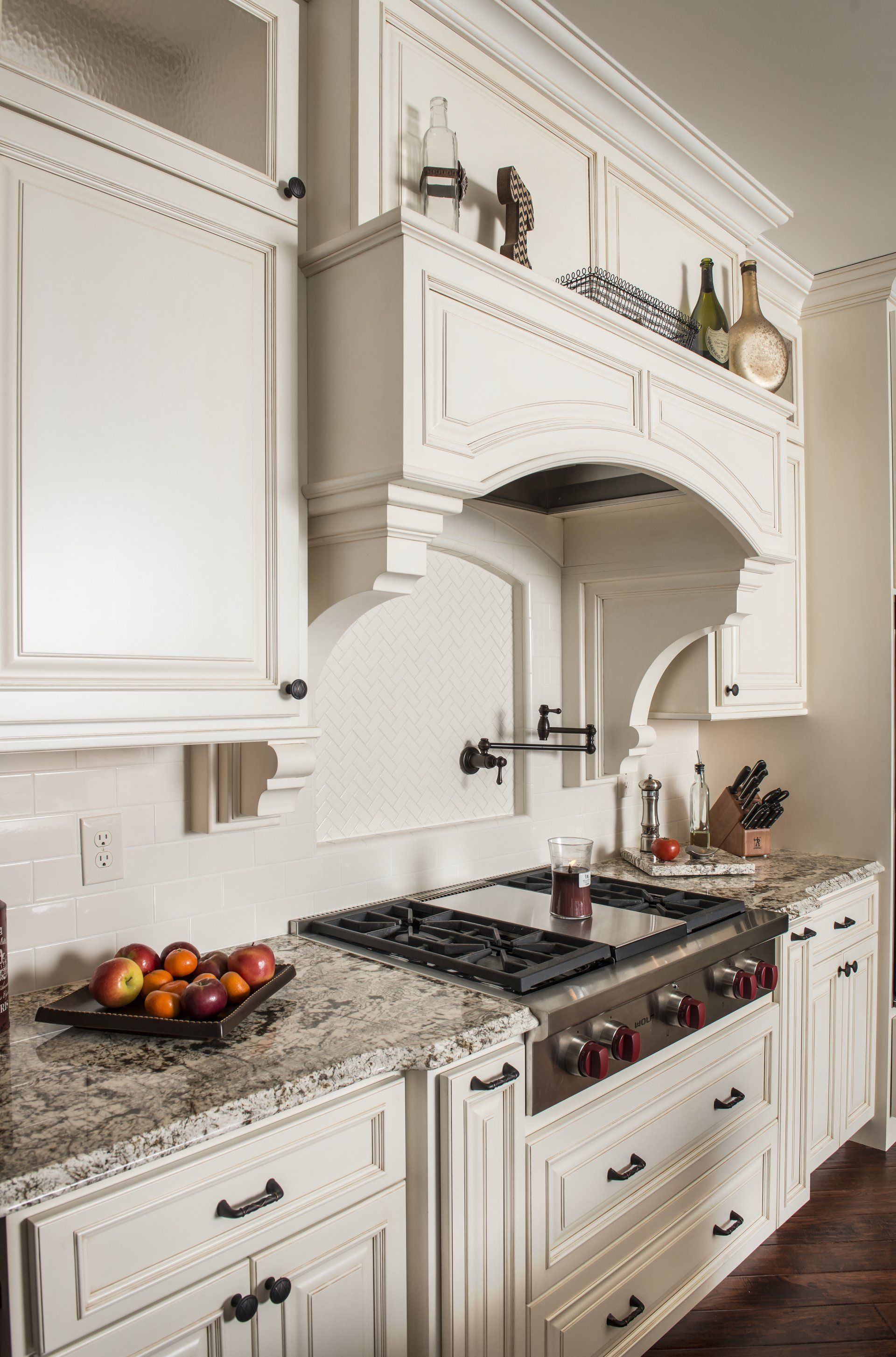 A kitchen with white cabinets and a stove top oven.