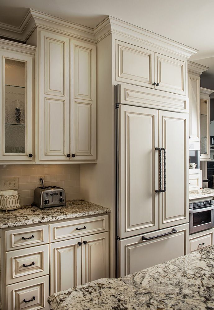 A kitchen with white custom cabinets and granite counter tops.