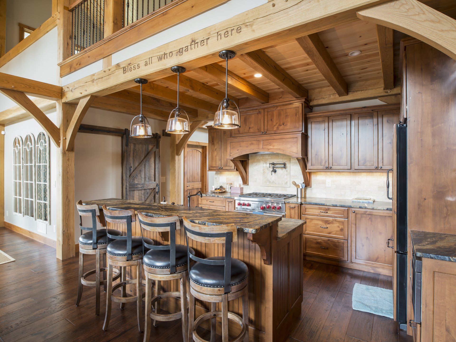 A kitchen with wooden cabinets and stools and a large island.