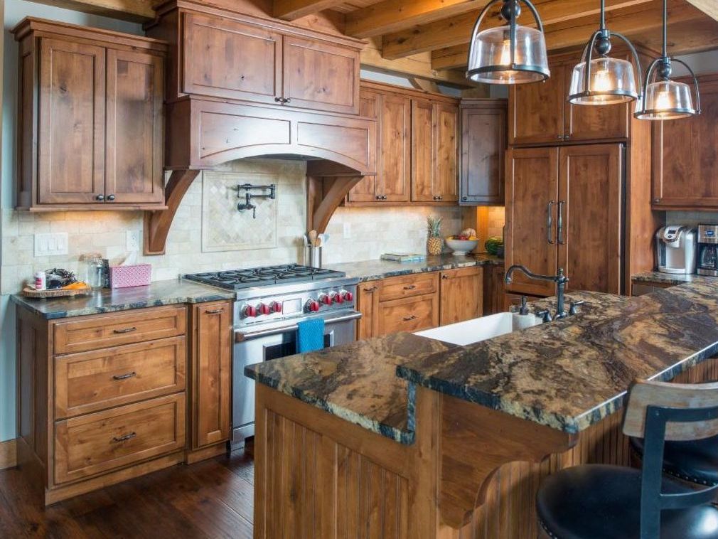 A kitchen with wooden cabinets , granite counter tops , a stove and a sink.