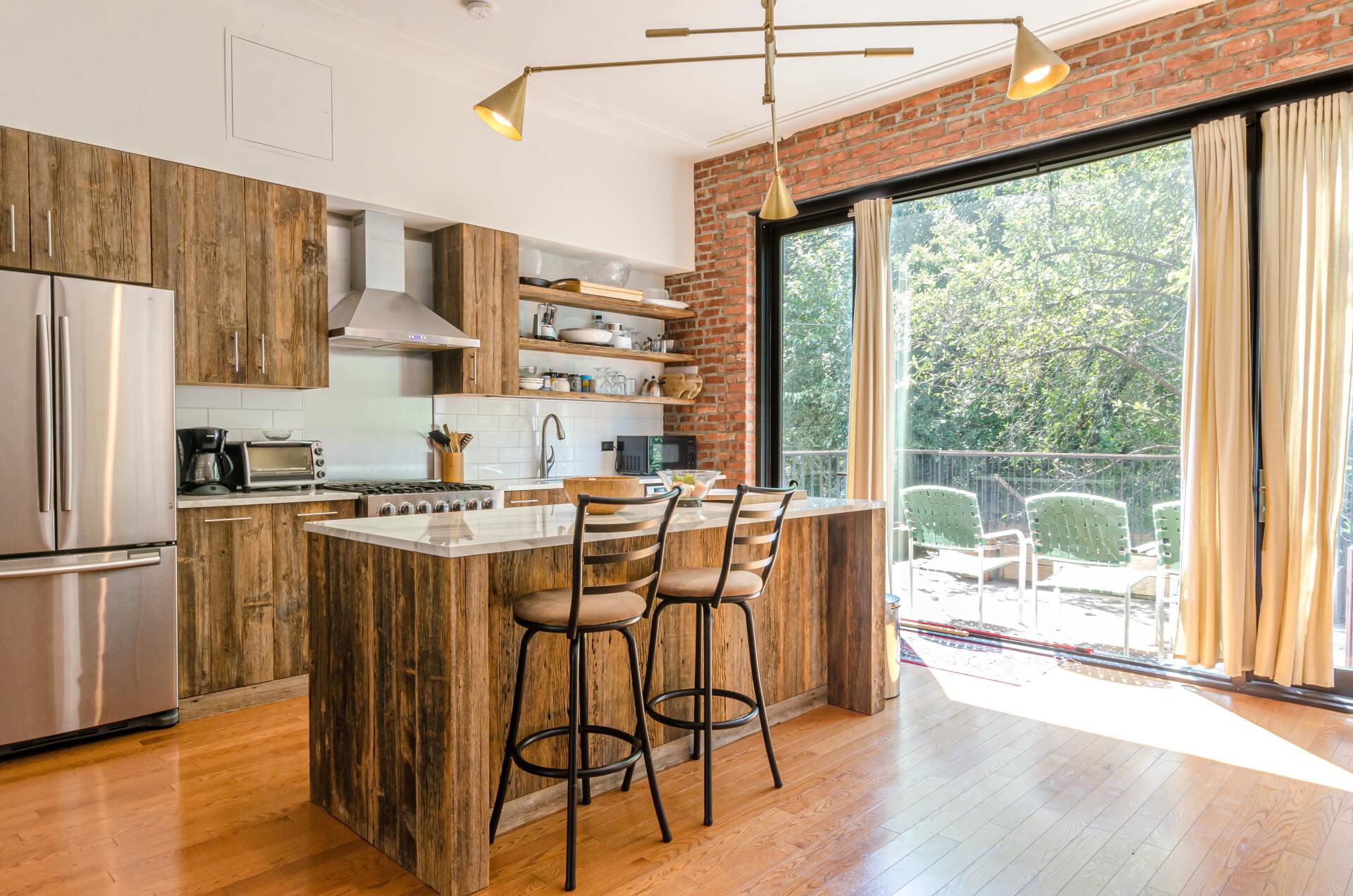 A kitchen with stainless steel appliances, wooden cabinet , and a large island.