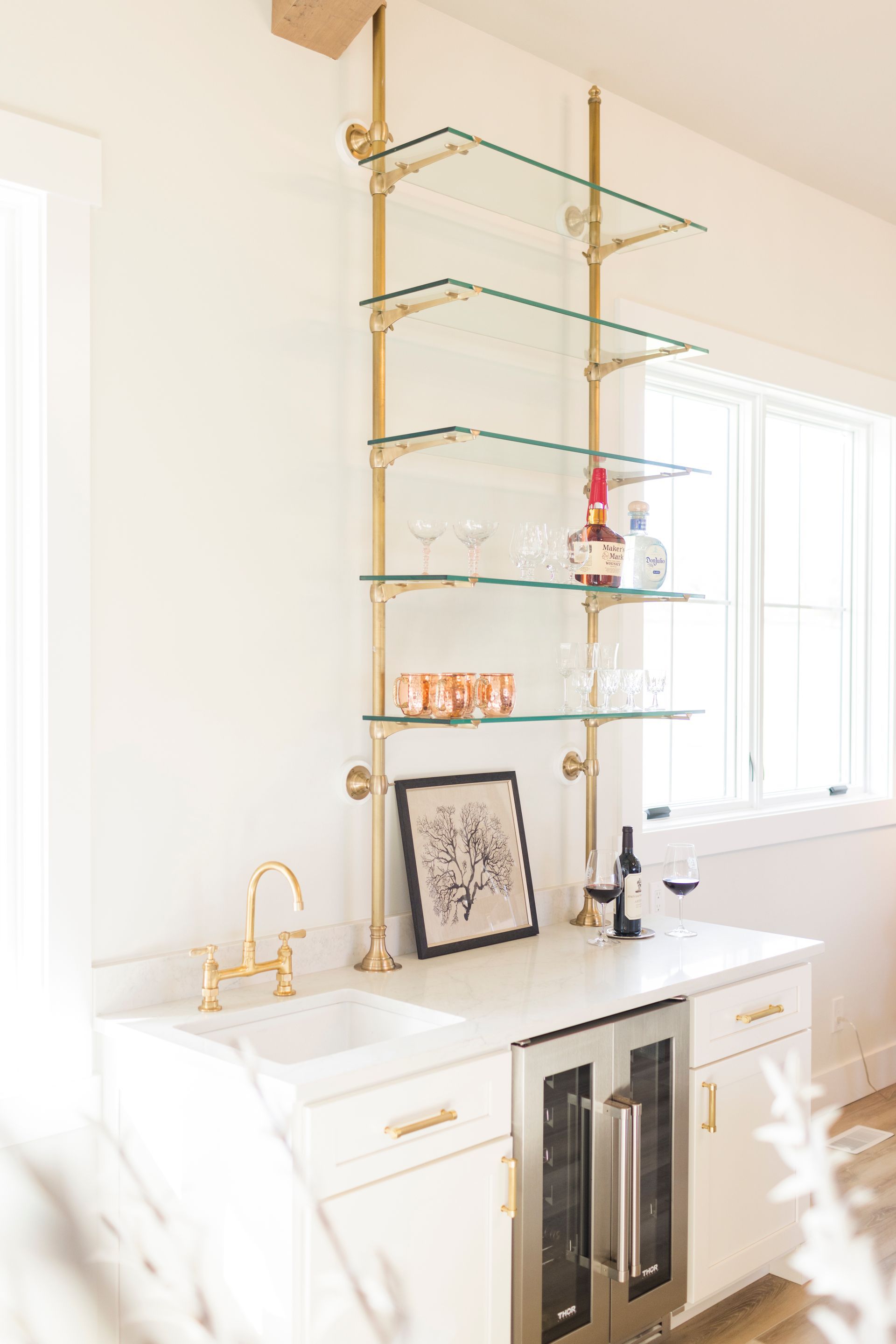 A kitchen with a sink , refrigerator , shelves and a window.