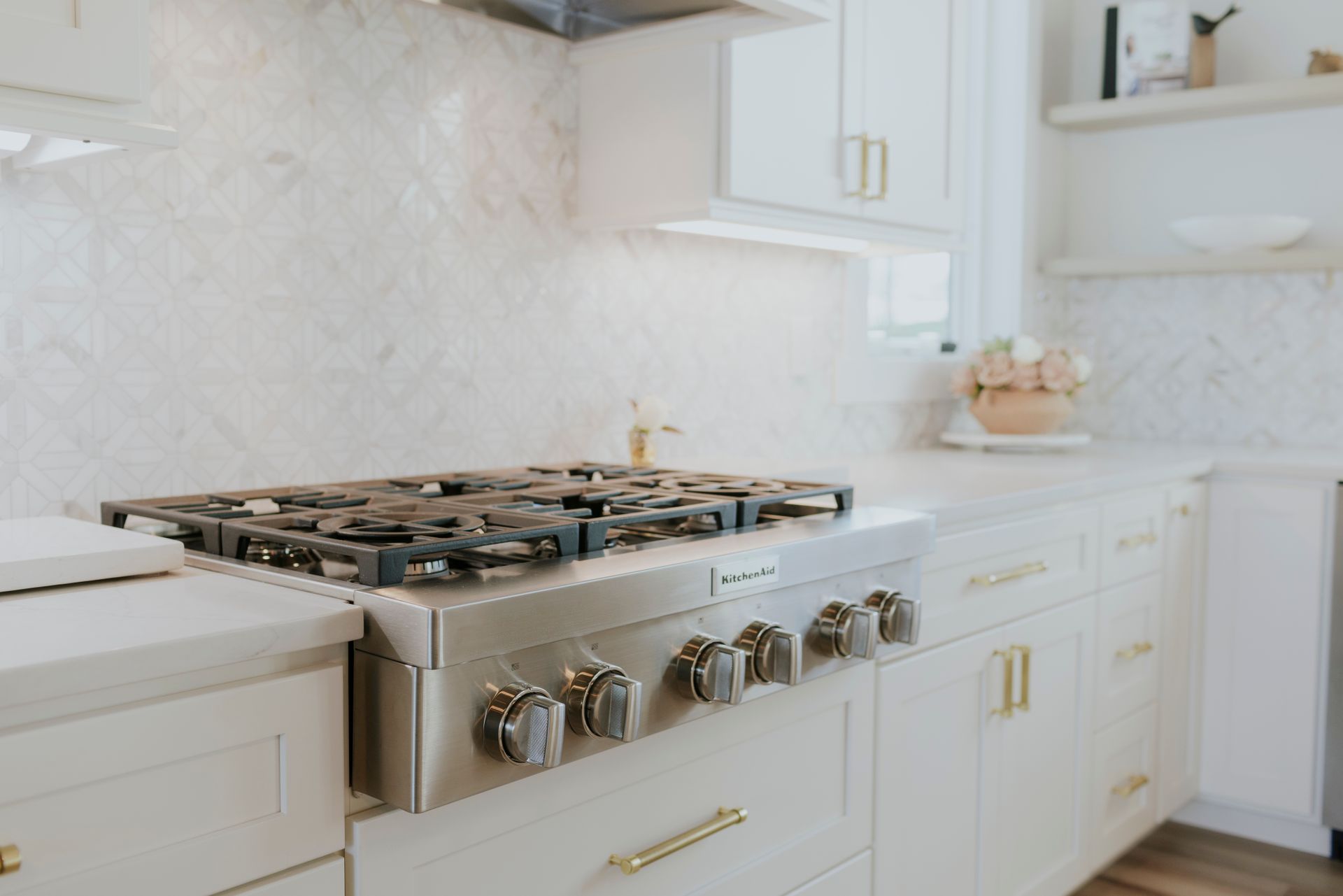 A kitchen with white cabinets and a stove top oven.