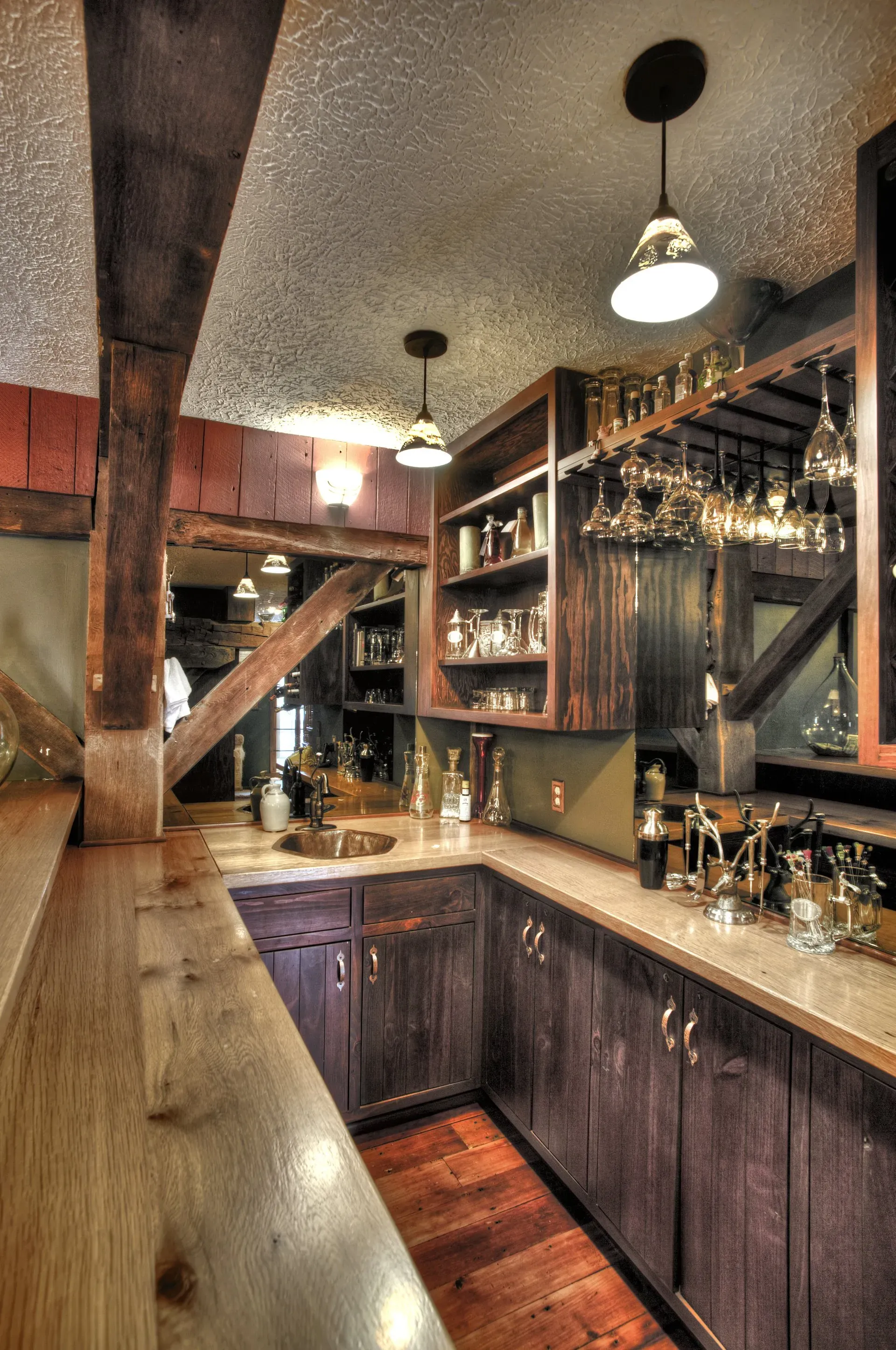 A kitchen with wooden cabinets and a bar with wine glasses on it.
