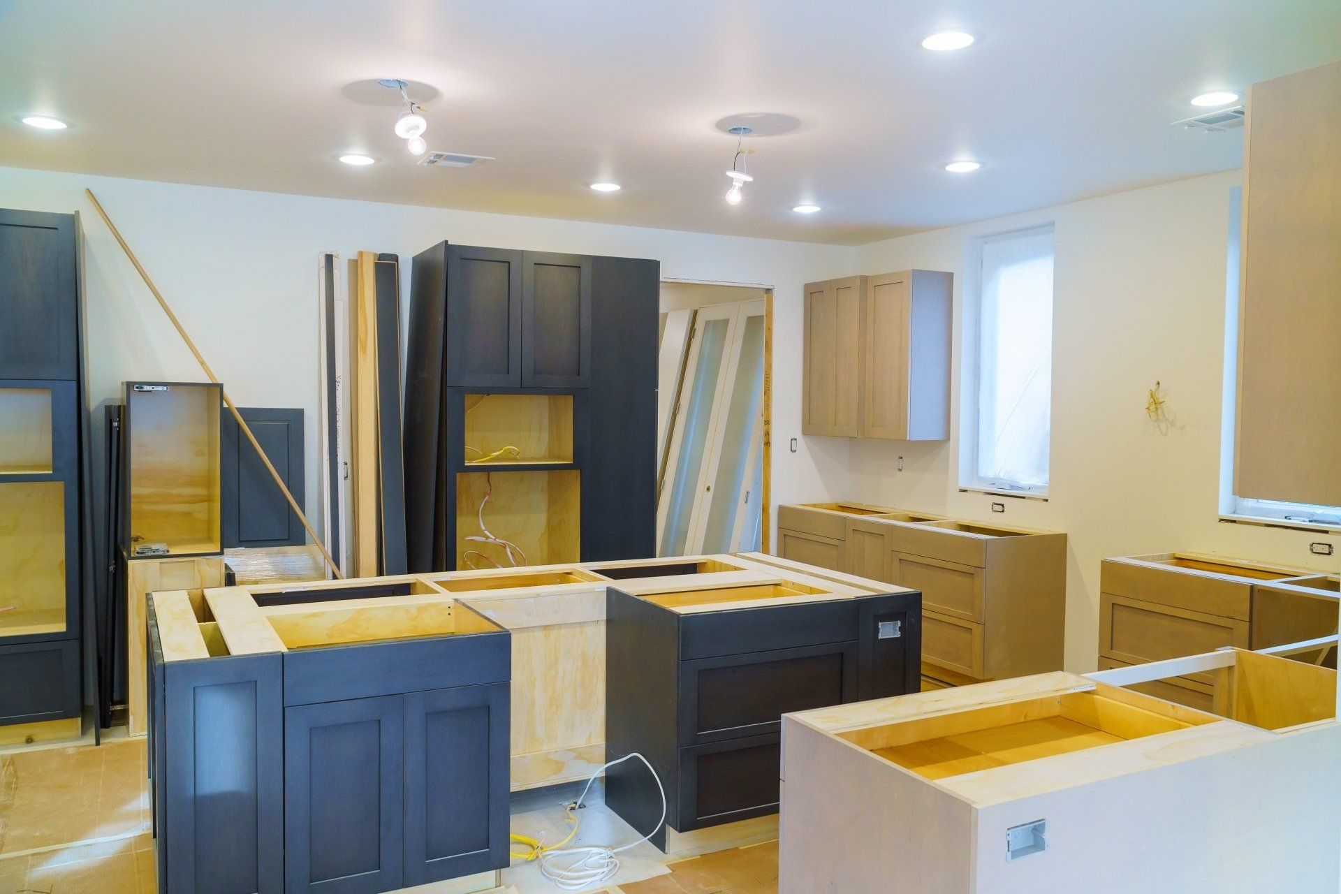 A kitchen under construction with lots of blue custom cabinets.