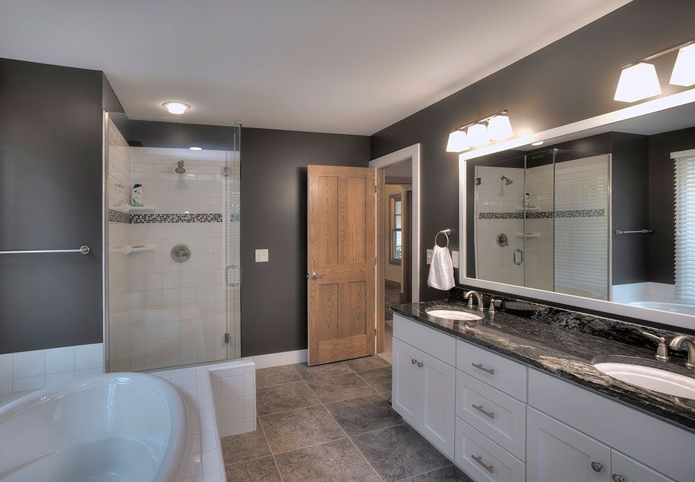 A bathroom with two sinks , a tub and a walk in shower.