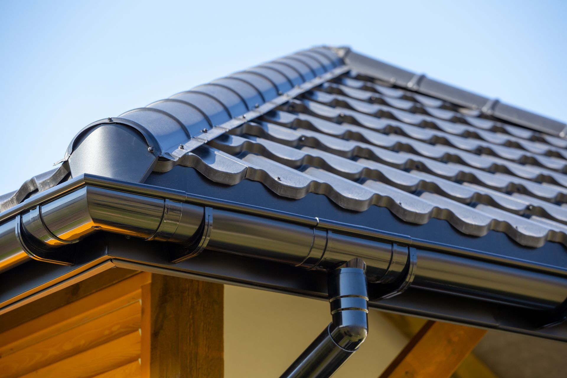 Metal roof with tiled shingles and installed gutter system along the edge