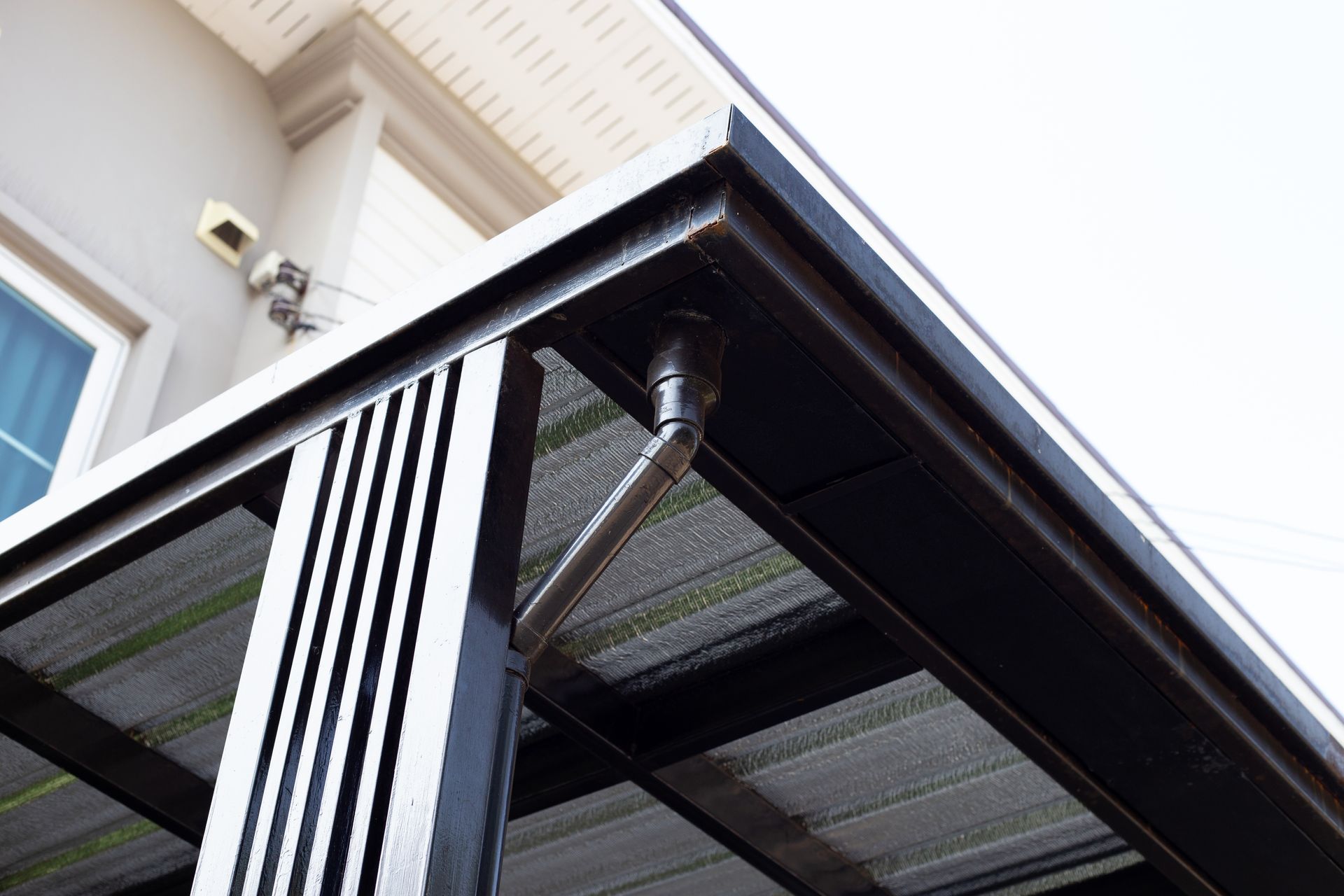 Close-up of a modern black awning with striped curtains under a building eave Close-up of a modern black awning with striped curtains under a building eave