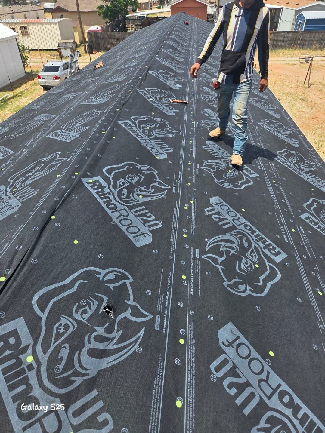 A person standing on a rooftop covered in Rhino Roof underlayment.