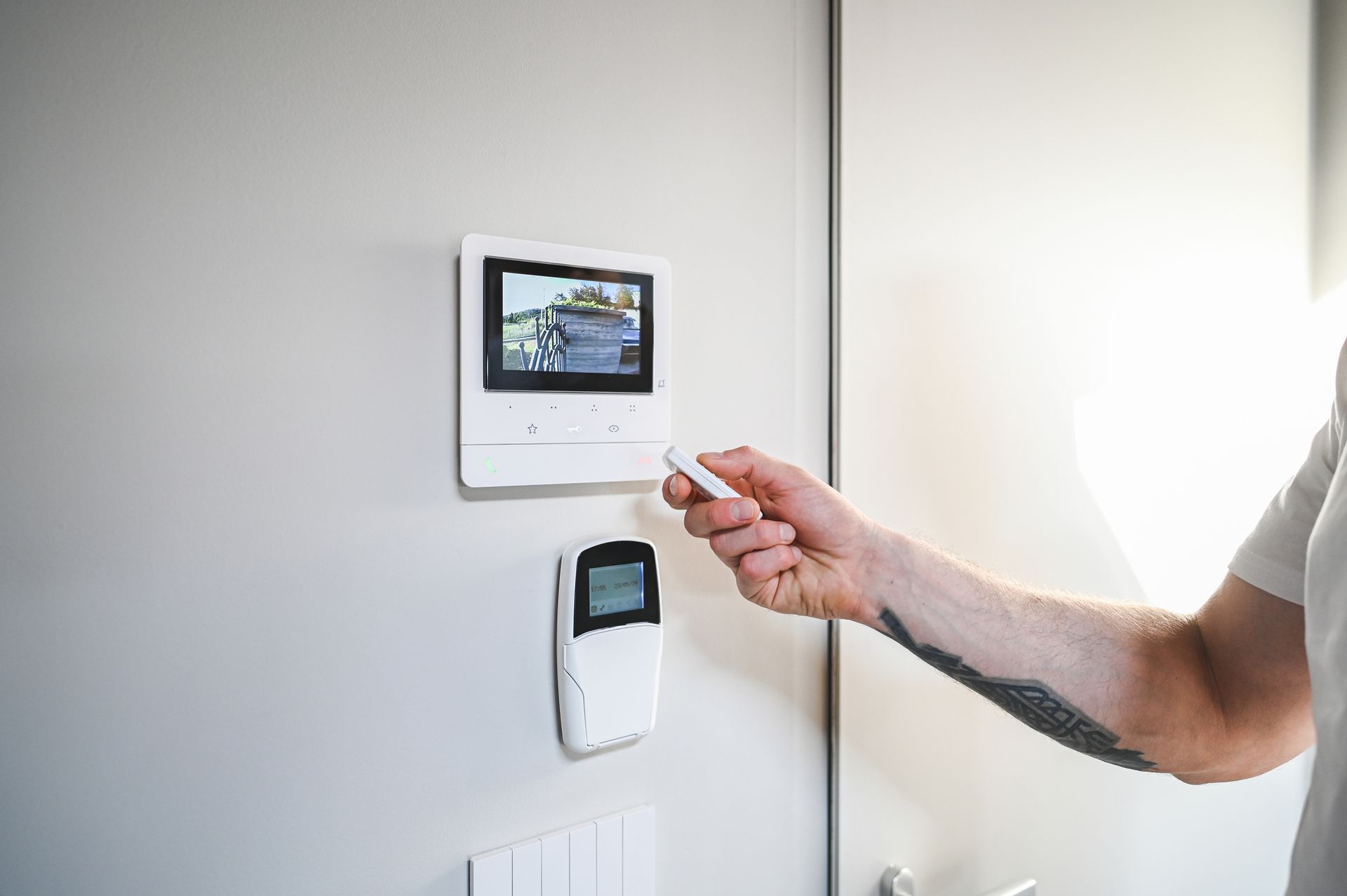 Person using a remote control to view a security camera feed on a wall-mounted monitor.