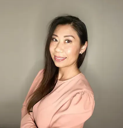 The woman is wearing a pink shirt and smiling for the camera.