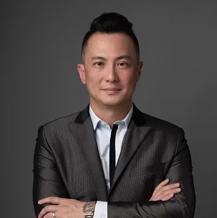 A man in a suit and tie is standing with his arms crossed.