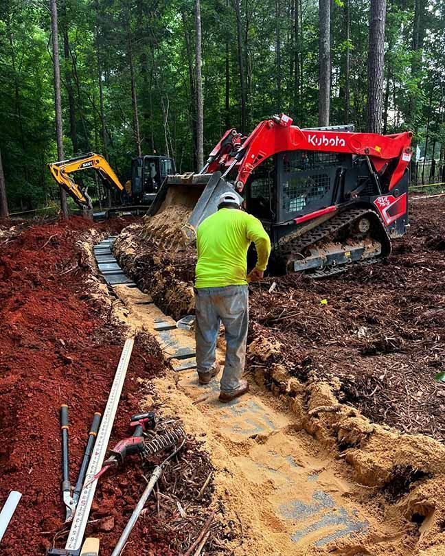 A man is standing in the dirt next to a bulldozer.