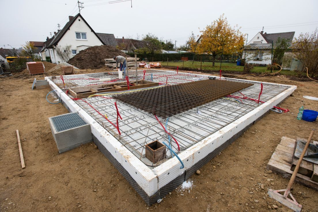 A concrete base for a house is being built in a dirt field.