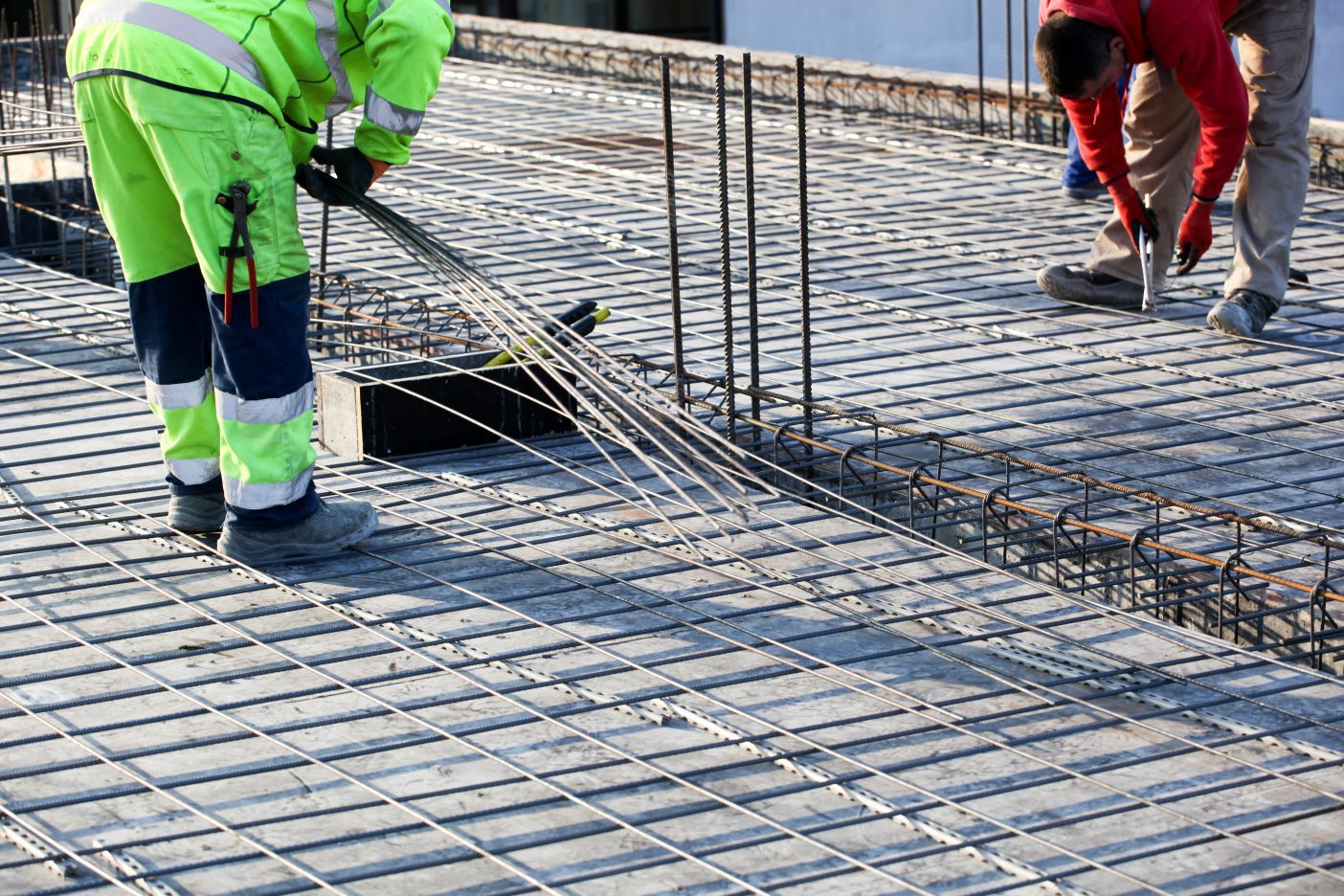 A group of construction workers are working on a concrete floor.