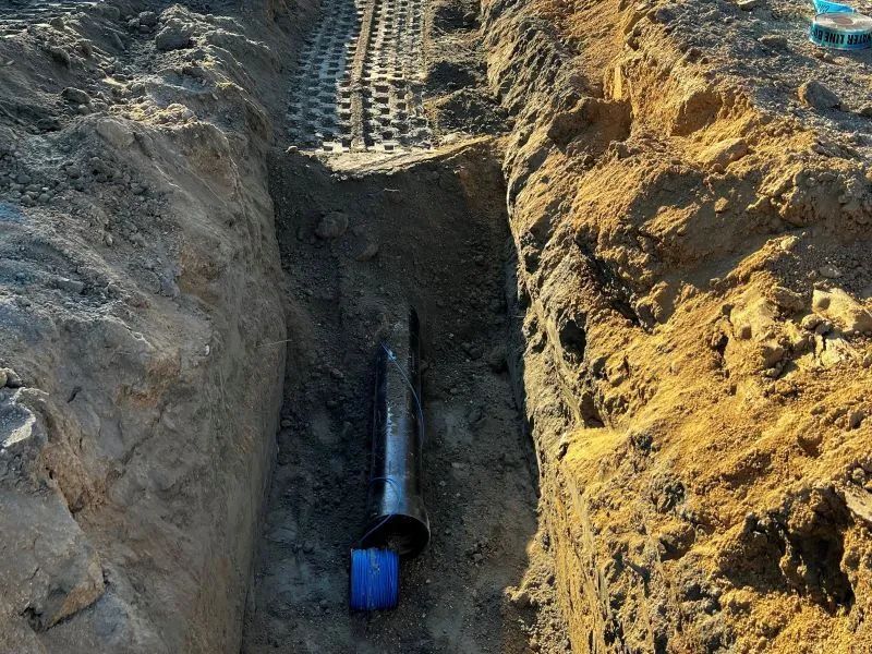 A pipe is being installed in a trench in the dirt.
