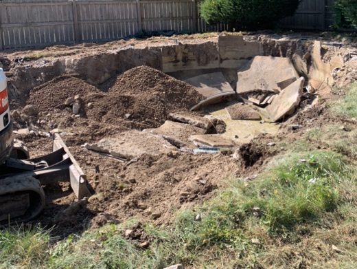 A bulldozer is digging a hole in the ground in a yard.