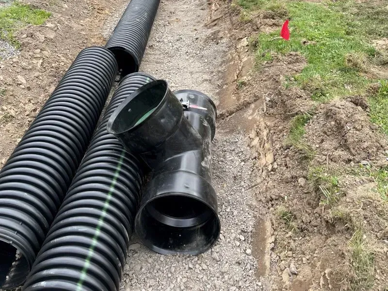 A bunch of black pipes are laying on the ground.
