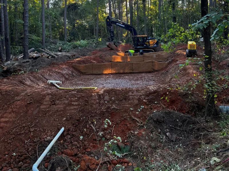 A large excavator is digging a hole in the middle of a forest.