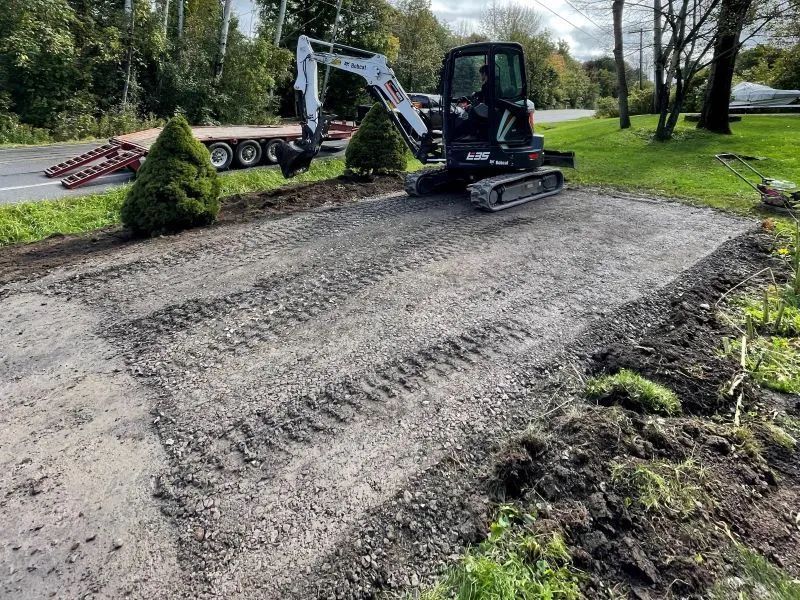 A small excavator is sitting on top of a dirt road.