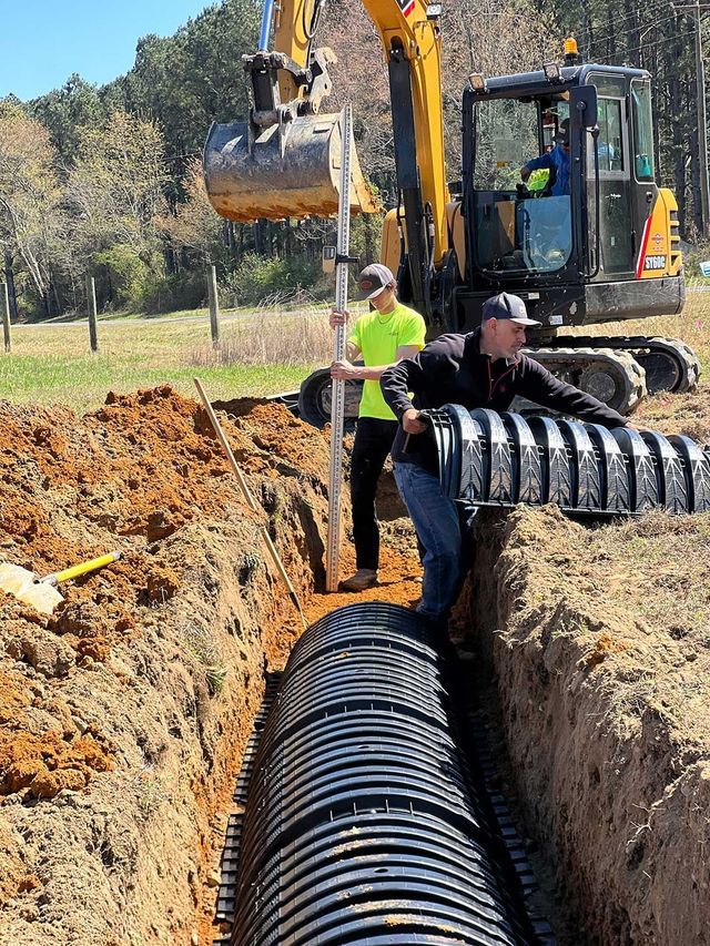 A man is standing next to a large pipe in the dirt.