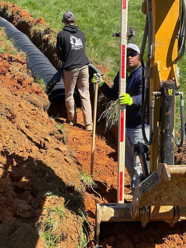 A man is standing next to a bulldozer holding a measuring stick.