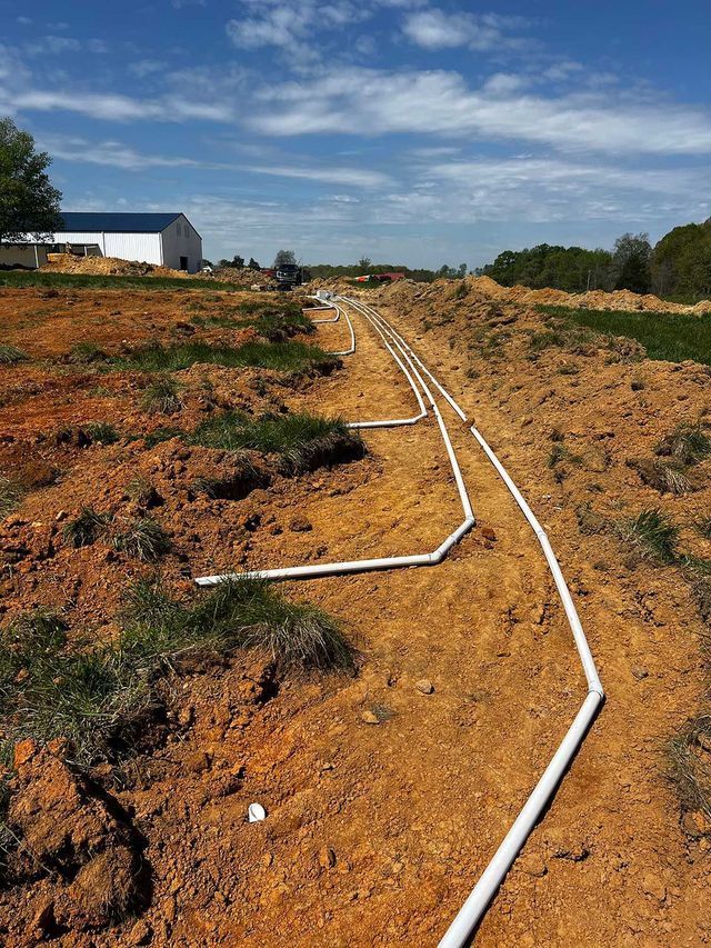 A hose is laying in the dirt in a field.