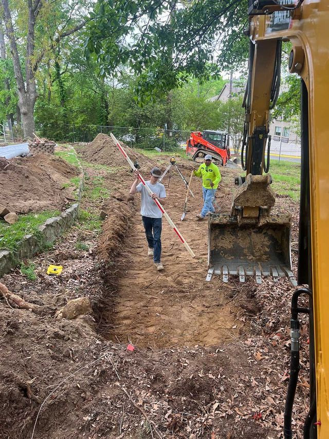 A man is standing in the dirt next to a bulldozer.