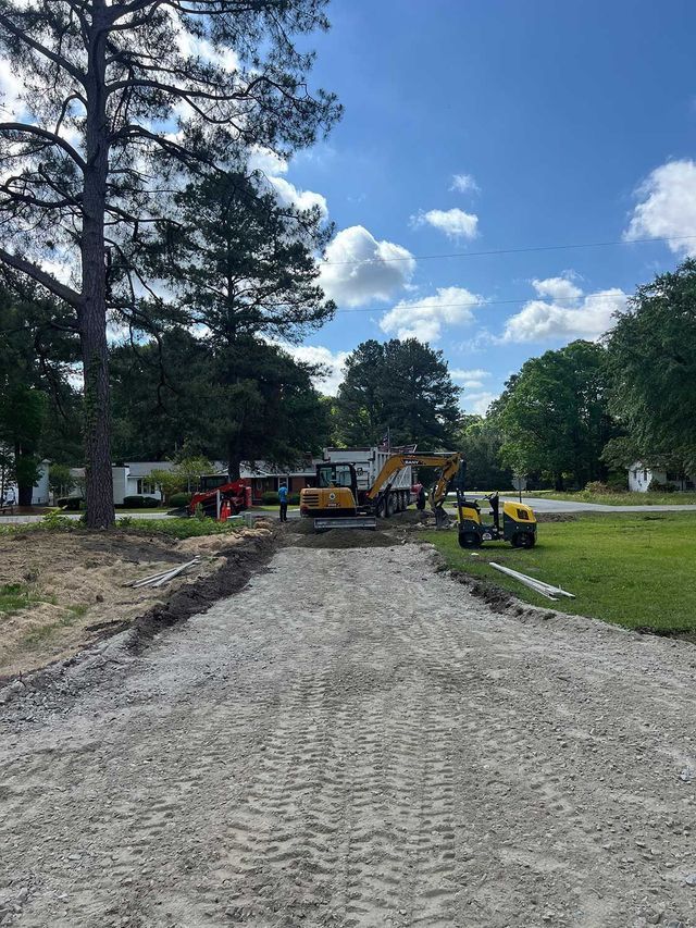 A dirt road with a yellow excavator on the side of it.
