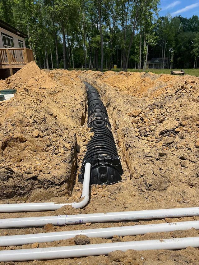 A septic tank is being installed in the dirt next to a house.