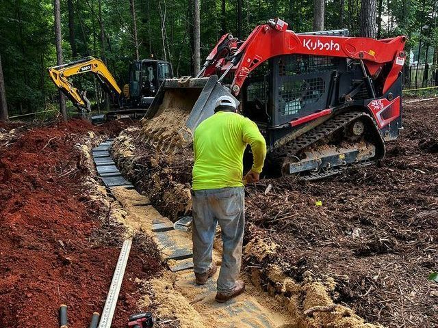 A man is standing in the dirt next to a bulldozer.