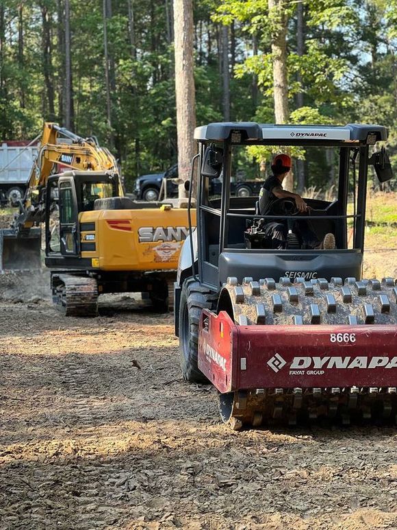 A man is driving a bulldozer in a dirt field.