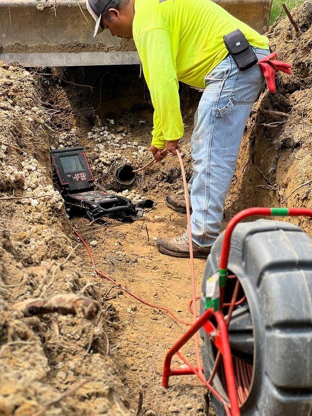 A man is standing in the dirt looking at a camera.