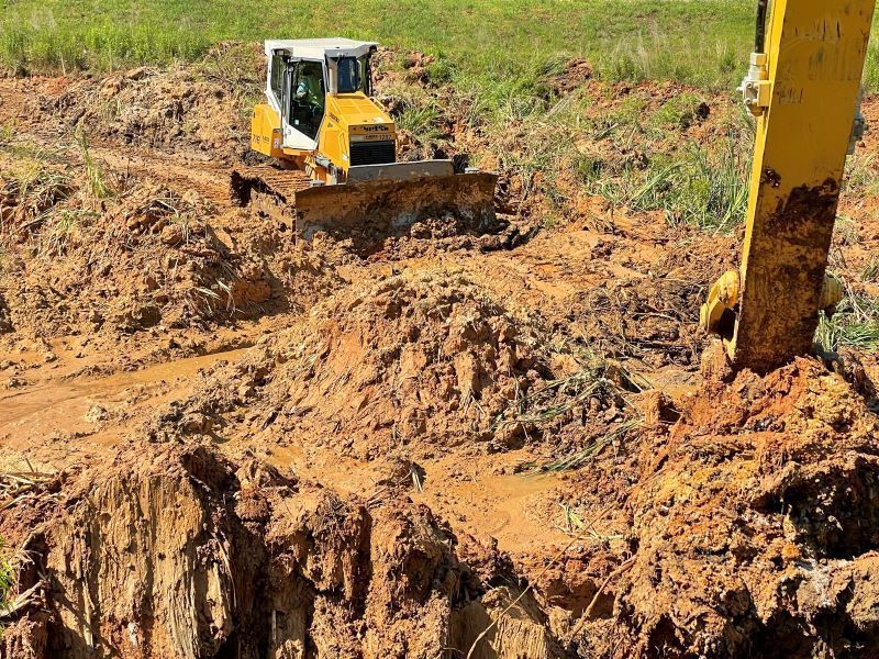 A bulldozer is digging a hole in the dirt in a field.