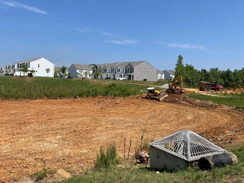 A construction site with a lot of dirt and buildings in the background