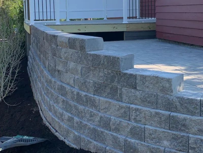 A brick wall surrounding a patio next to a house.