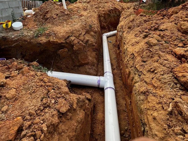 A white pipe is being installed in a hole in the ground.